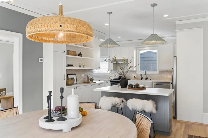 Kitchen featuring custom shaker-style cabinetry, a central island with a quartz countertop, built-in open shelving, decorative woven and metal pendant lighting, and wood-finish flooring