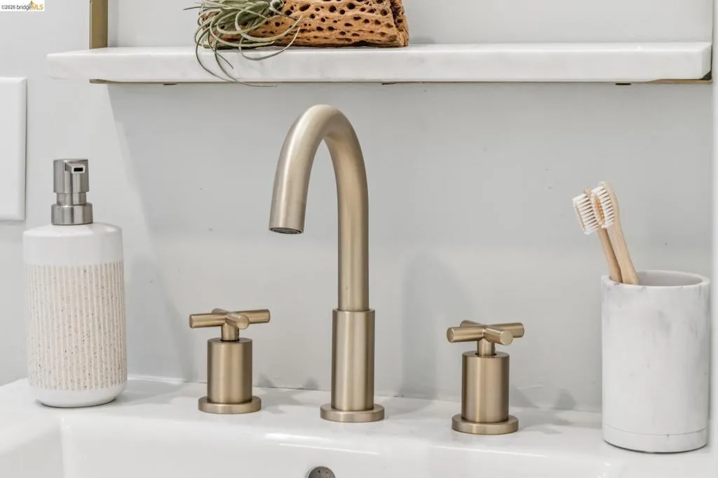 Widespread bathroom faucet in a brushed gold finish featuring cross-handle controls and a floating stone-surface shelf