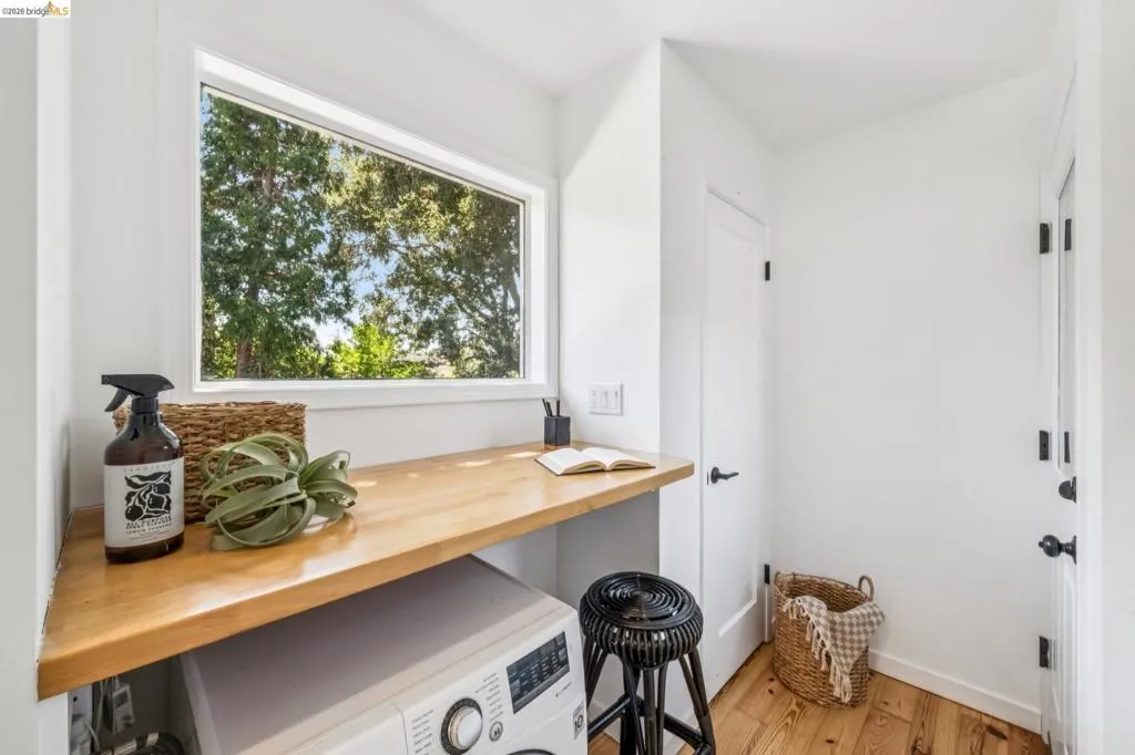Built-in wood-finish countertop, washer/dryer combo, single-pane window, and wood-finish flooring