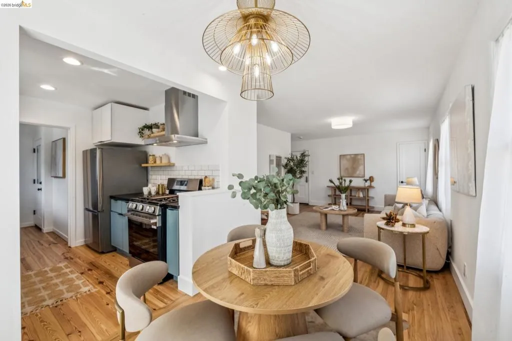 Kitchen featuring stainless steel appliances, a chimney-style range hood, subway tile backsplash, wood-finish flooring, and a decorative metallic pendant light fixture