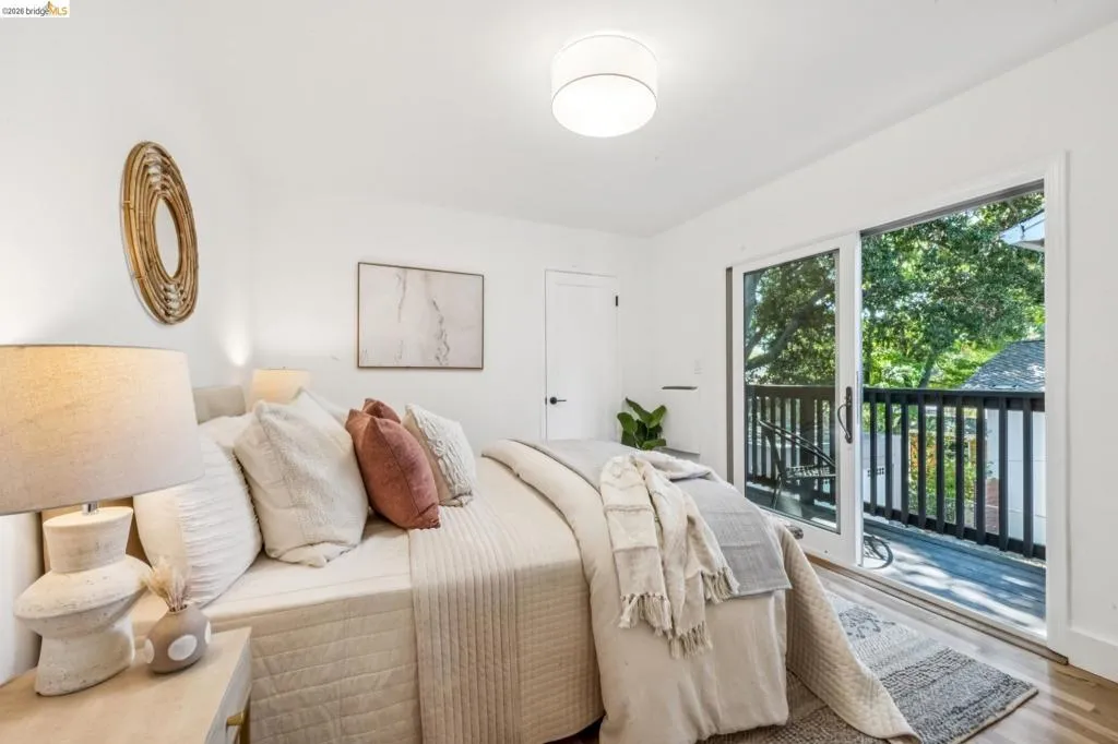 Bedroom featuring wood-finish flooring, a drum-style ceiling light fixture, and sliding glass doors with direct access to a balcony with dark-toned railings
