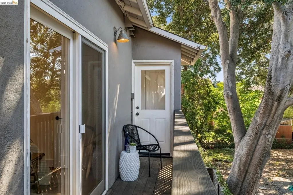 Exterior deck featuring wood-finish flooring, a metal railing, glass sliding doors, and an attached wall-mounted exterior light fixture