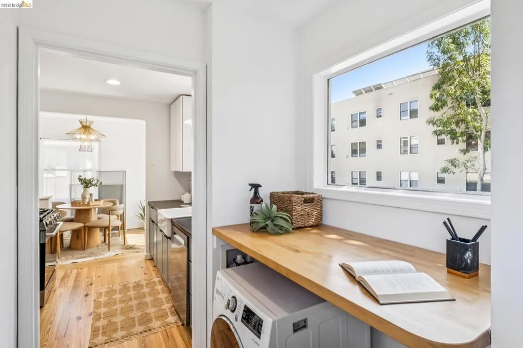 Laundry space featuring a natural wood-finish countertop, washer/dryer combo and a large horizontal window providing natural light