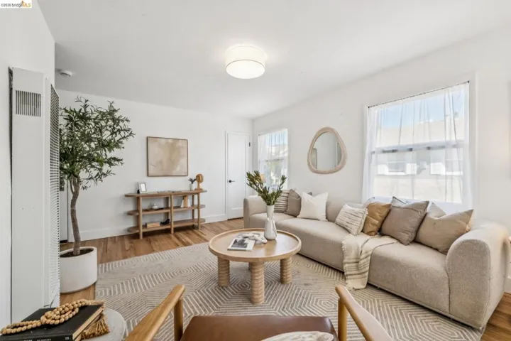 Living area featuring wood-finish flooring, two dual-pane windows with natural light, and a flush-mount drum ceiling light fixture