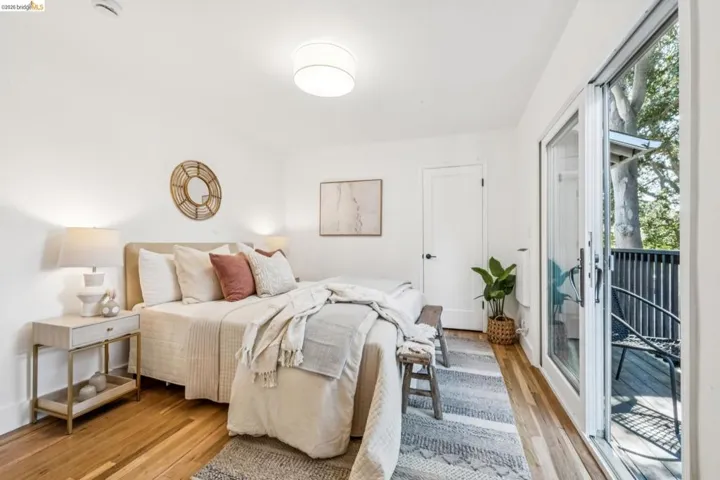 Wood-finish flooring, sliding glass door access to a private balcony, flush-mount lighting, and solid-core interior door