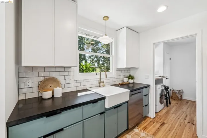 Kitchen featuring matte-finish countertops, subway tile backsplash, farmhouse-style sink, white upper cabinetry, and wood-finish flooring