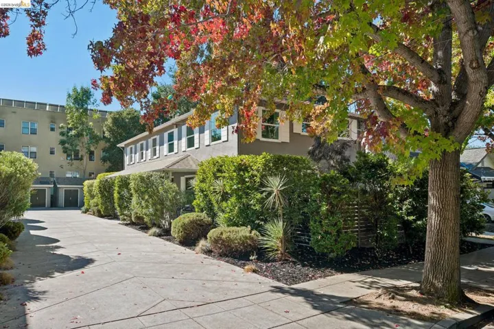 Exterior featuring a multi-story structure with shuttered windows, concrete driveway, and mature landscaping