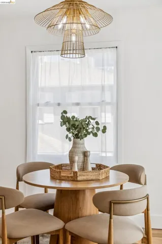 Multi-tiered gold-tone metal pendant light fixture and a single-hung window with white casing