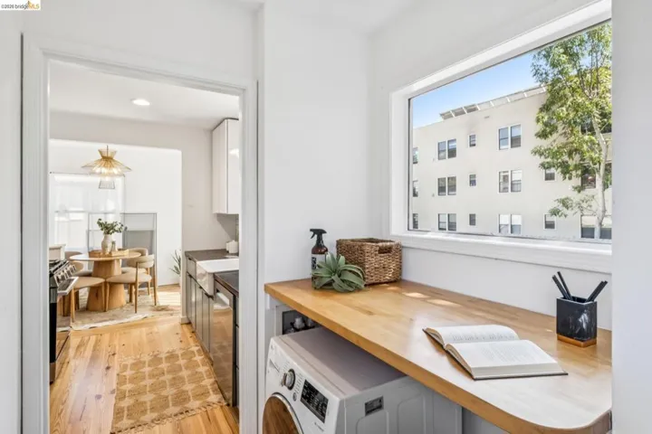 Laundry space featuring a natural wood-finish countertop, washer/dryer combo and a large horizontal window providing natural light