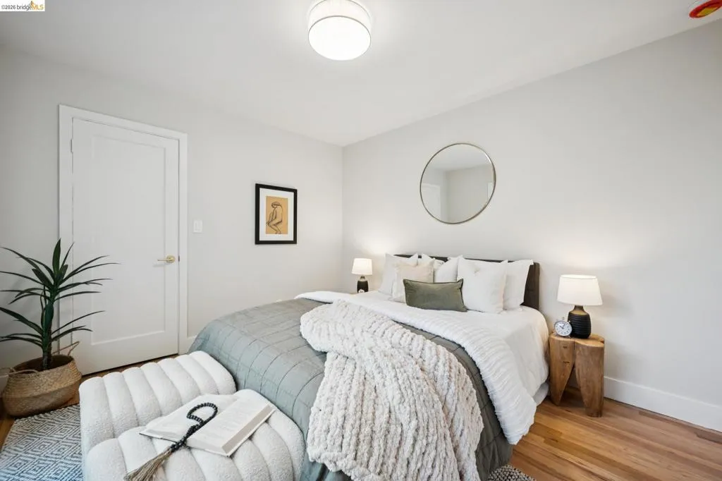 Neutral-toned interior featuring wood-finish flooring, a contemporary drum flush-mount light fixture, and a circular wall-mounted mirror