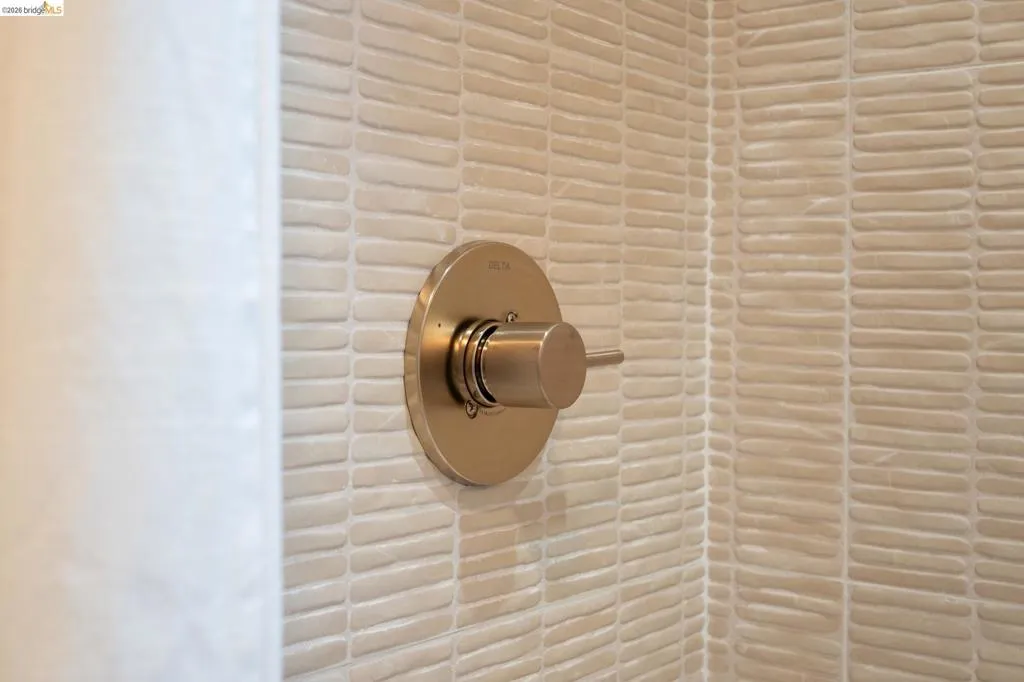 Textured ceramic tile surround with a brushed metallic single-handle shower control valve