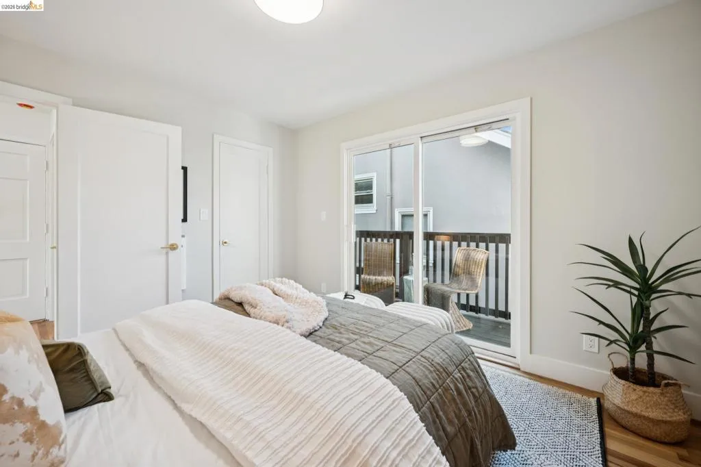 Sliding glass door with access to an exterior balcony, light-toned walls, wood-finish flooring, and two interior solid-core doors