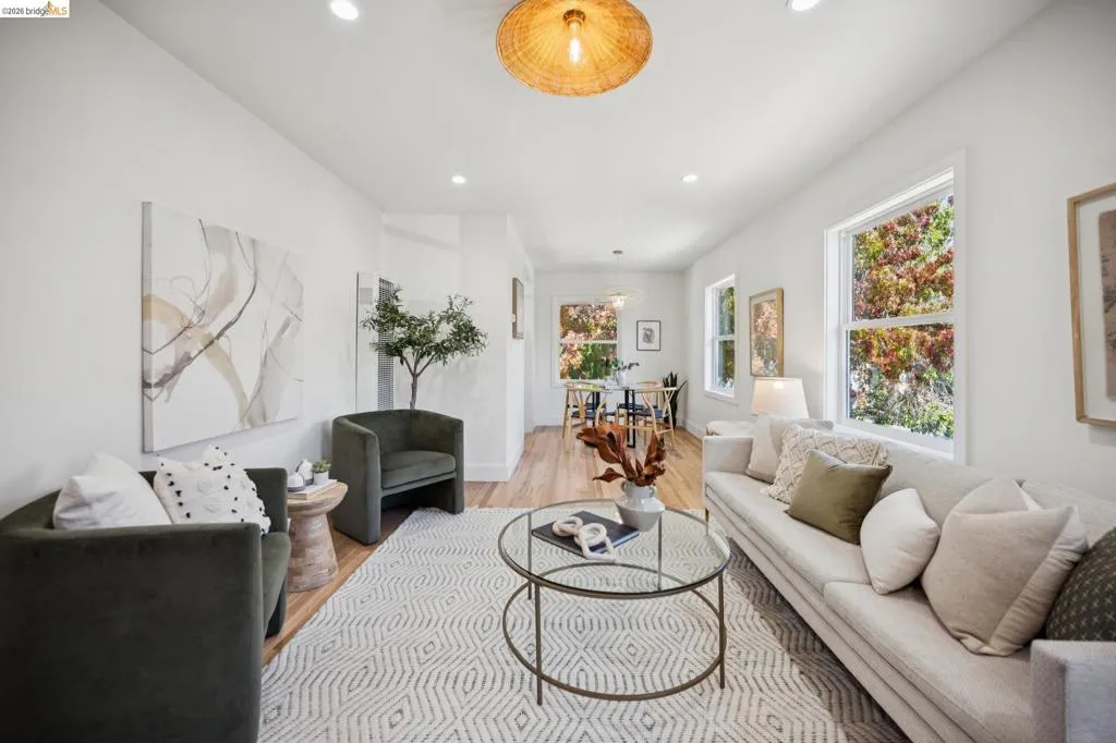 Living space featuring wood-finish flooring, recessed lighting, a woven drum pendant light, and large windows