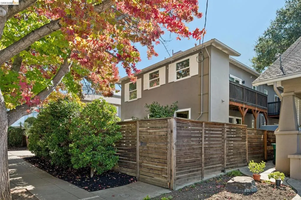 Two-story exterior featuring a horizontal wood slat fence, second-level wooden balcony, and white-framed windows