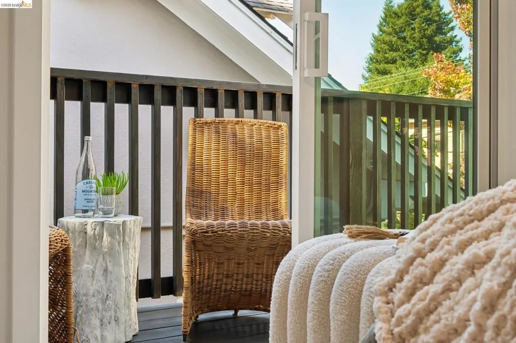 Covered balcony featuring dark-finish wood flooring and vertical slat railing with a sliding glass door entry