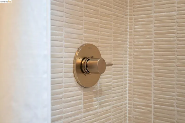 Textured ceramic tile surround with a brushed metallic single-handle shower control valve