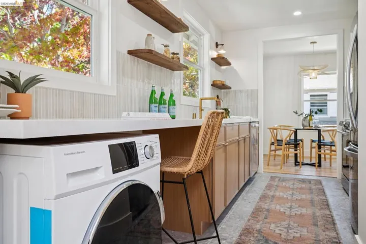 Kitchen featuring light wood cabinetry, quartz countertops, vertical tile backsplash, wall-mounted open shelving, and recessed lighting