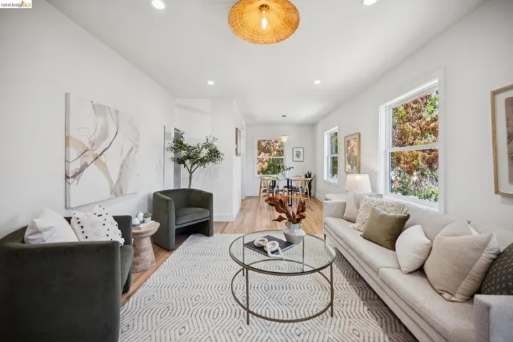 Living space featuring wood-finish flooring, recessed lighting, a woven drum pendant light, and large windows