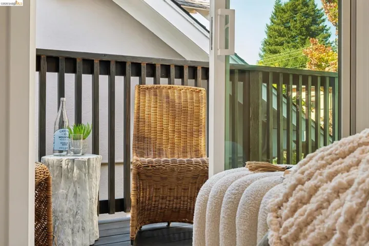 Covered balcony featuring dark-finish wood flooring and vertical slat railing with a sliding glass door entry