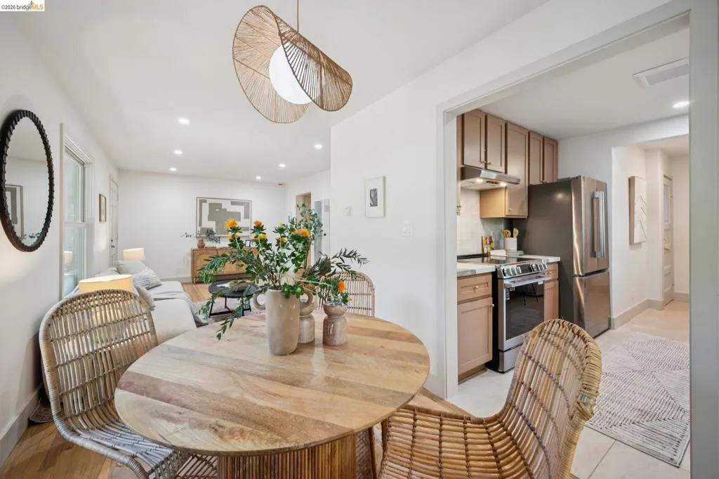 Recessed lighting, arched woven pendant light fixture, stainless steel kitchen appliances, and wood-finish flooring