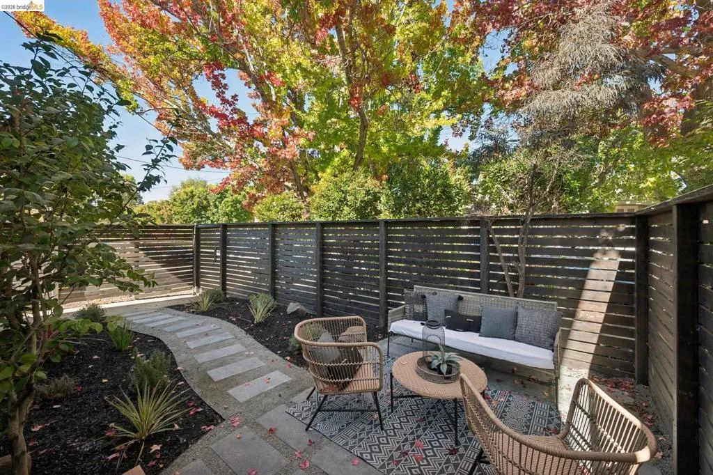 Private outdoor space featuring horizontal wood slat fencing, a stone paver path, and mature tree canopy