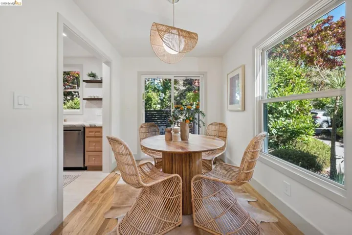 Dining area featuring wood-finish flooring, a contemporary pendant light fixture, sliding glass door, and large window with natural light