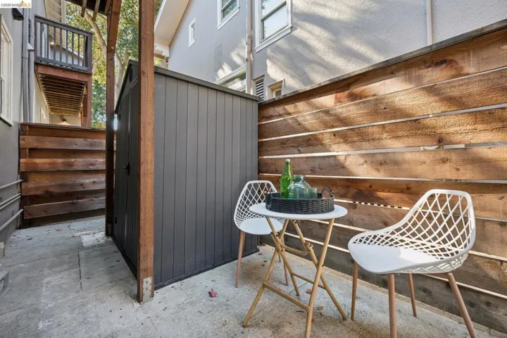 Exterior side yard featuring a concrete patio, horizontal slat wood privacy fencing, and a vertical-profile storage shed