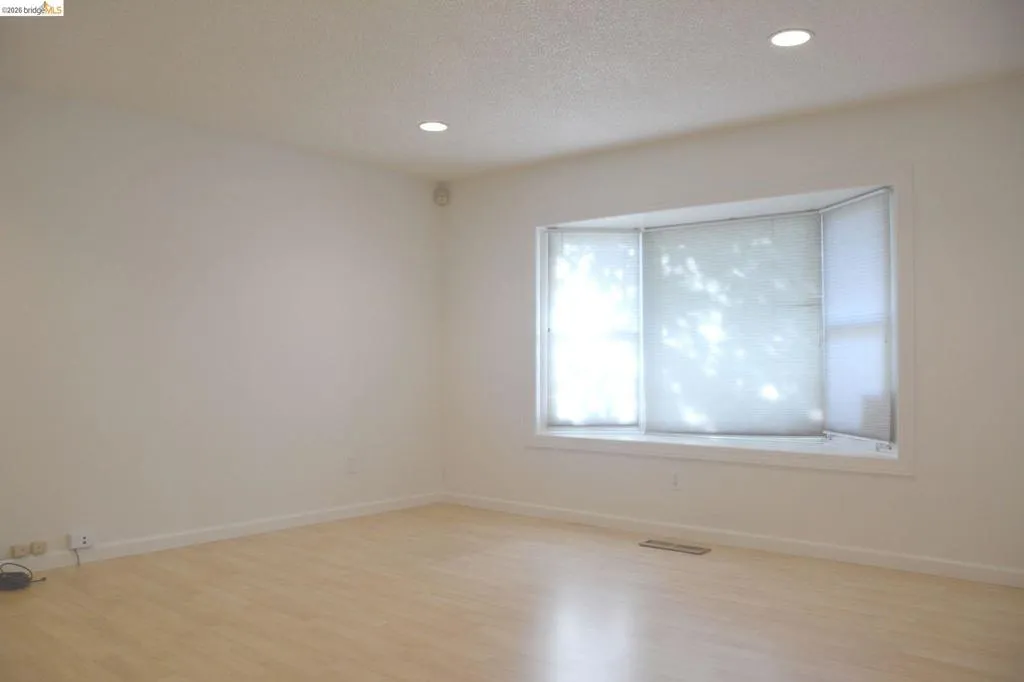 Spacious living room featuring a bay window, can lighting and laminate flooring.