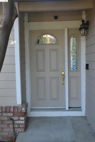 Front entry porch with single door entry with leaded half fan and partition wall windows.