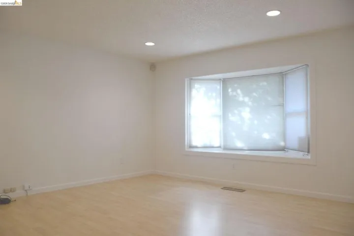 Spacious living room featuring a bay window, can lighting and laminate flooring.