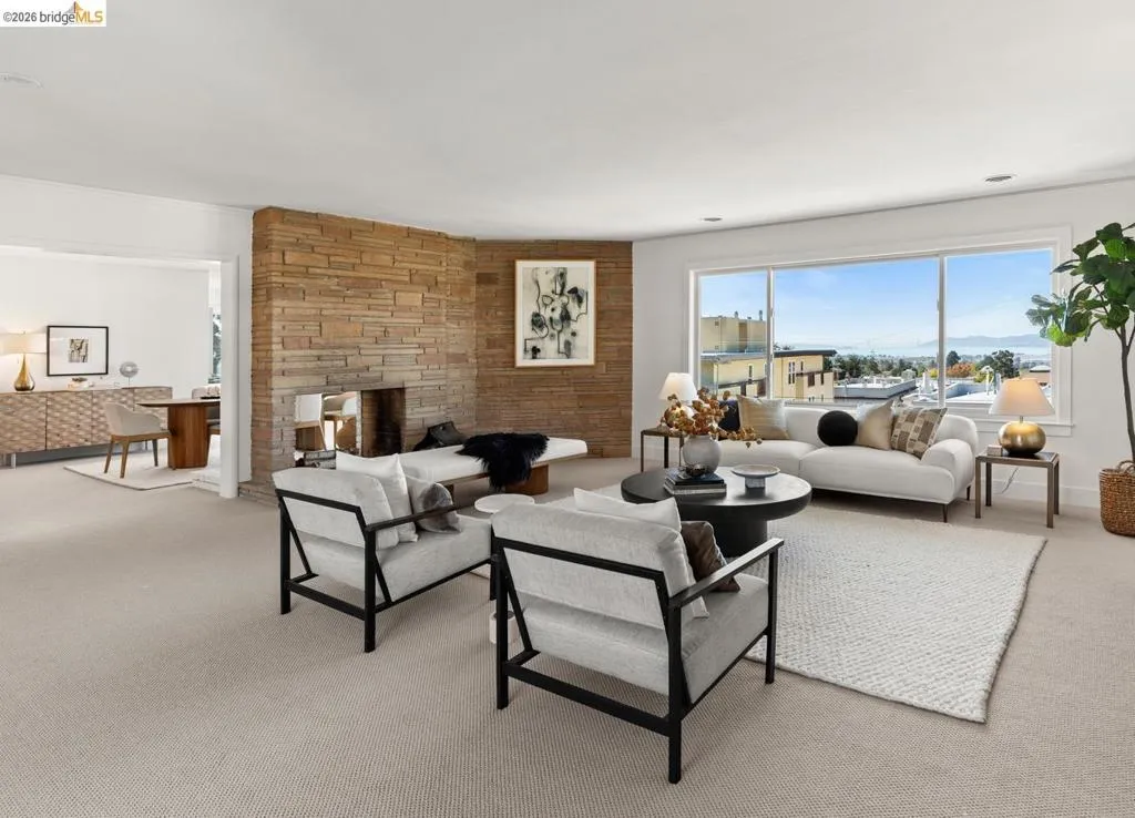 Living area featuring a floor-to-ceiling stone fireplace, large picture windows, and neutral carpeting