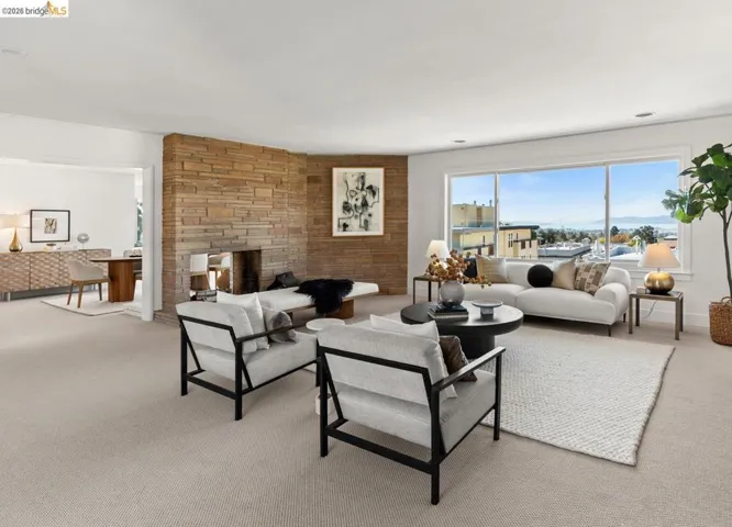 Living area featuring a floor-to-ceiling stone fireplace, large picture windows, and neutral carpeting