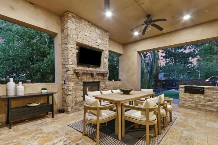 Covered loggia with stone fireplace and outdoor dining at twilight, Los Gatos