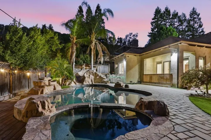 Pool waterfall and palms with the home at dusk, Los Gatos