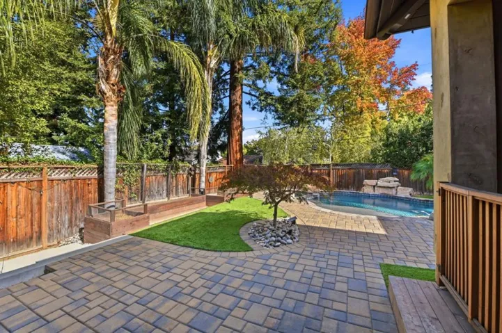 Backyard lawn and paver patio with pool in the distance, Los Gatos