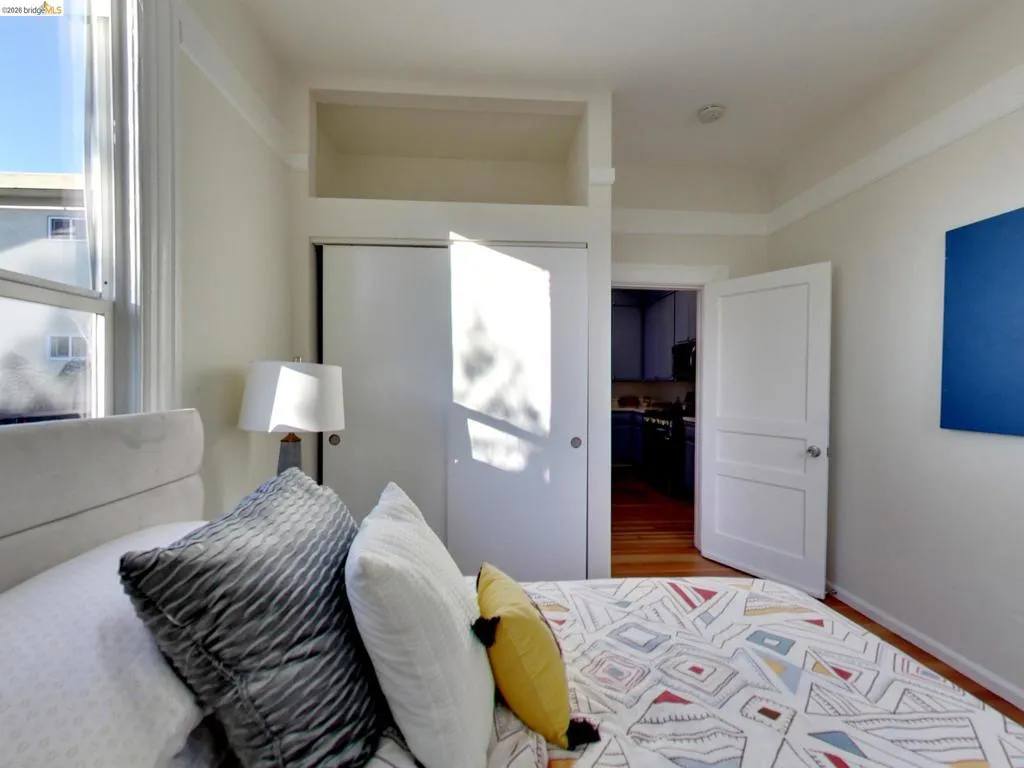 Room featuring wood-finish flooring, a built-in closet with overhead storage, a multi-pane window, and a paneled interior door Room featuring wood-finish flooring, a built-in closet with overhead storage, a multi-pane window, and a paneled interior door