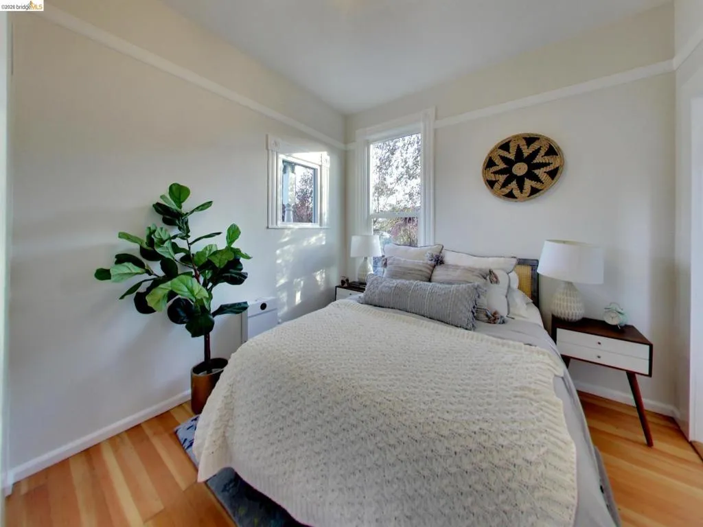 Room featuring wood-finish flooring, white wall trim, and oversized window casing Room featuring wood-finish flooring, white wall trim, and oversized window casing