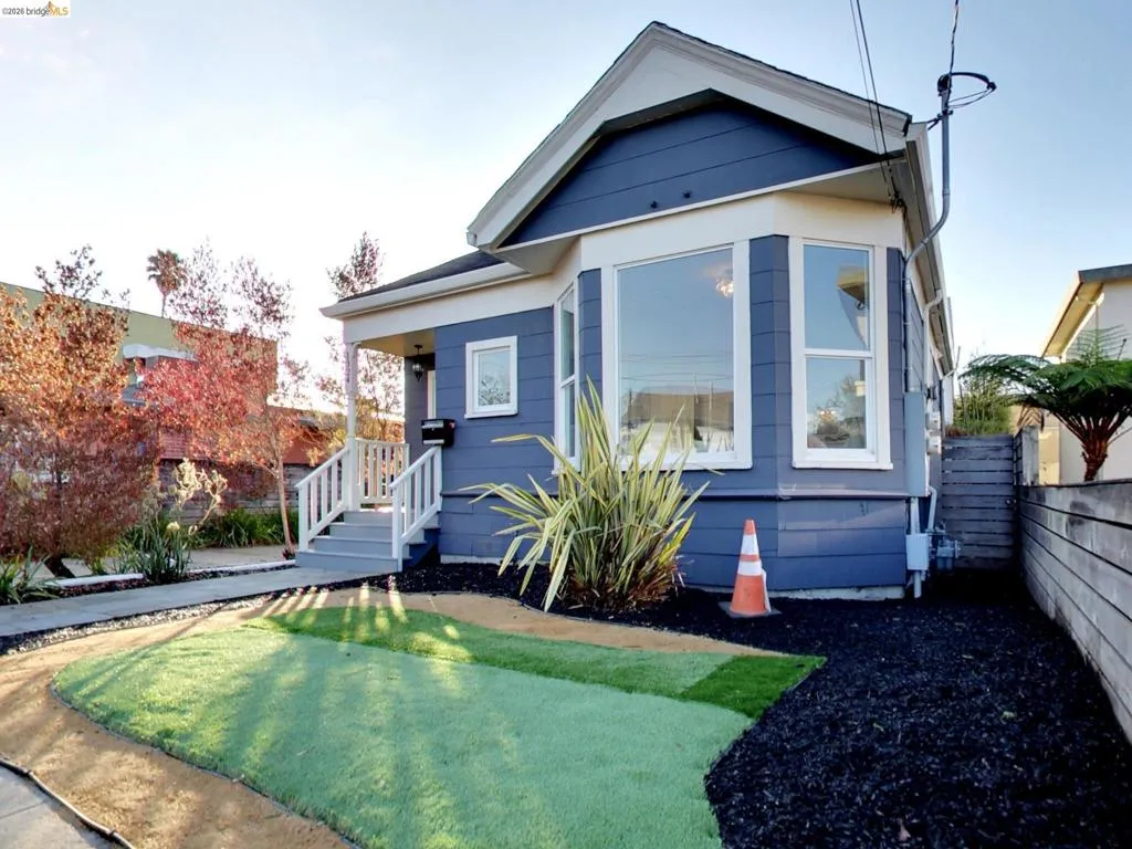Exterior featuring blue horizontal siding, a prominent bay window, white trim detailing, and a front porch with a white wood railing Exterior featuring blue horizontal siding, a prominent bay window, white trim detailing, and a front porch with a white wood railing