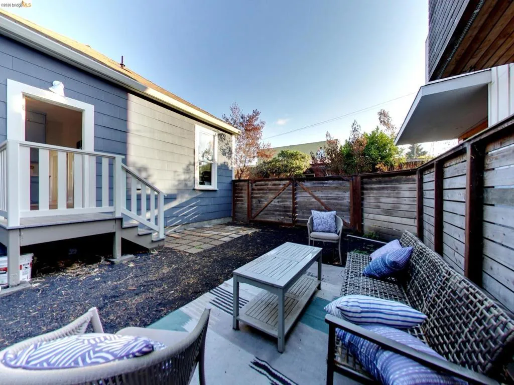 Private outdoor space featuring horizontal wood fencing, a paved stone patio, and a raised exterior deck with white railings Private outdoor space featuring horizontal wood fencing, a paved stone patio, and a raised exterior deck with white railings