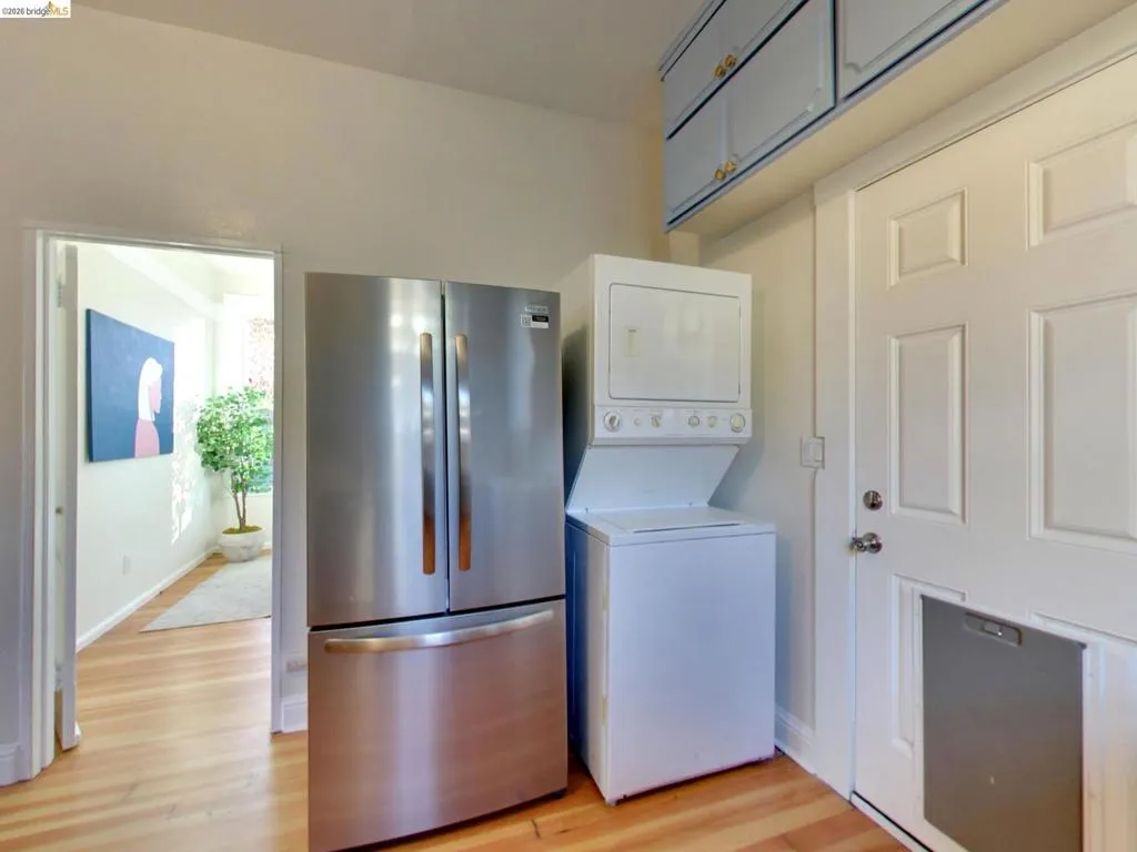 Stainless steel French door refrigerator, stackable laundry unit, overhead cabinetry, and exterior door with integrated pet door Stainless steel French door refrigerator, stackable laundry unit, overhead cabinetry, and exterior door with integrated pet door