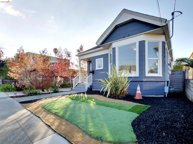 Single-story residence featuring blue horizontal siding, a gabled roofline, a bay window, and a white-painted wooden front porch railing