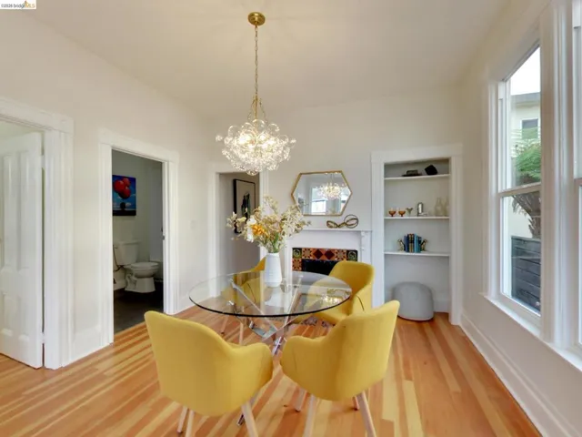 Light-filled room featuring wood-finish flooring, a decorative fireplace with colorful tile surround, built-in shelving, and a multi-globe pendant light fixture