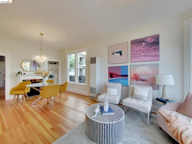 Living area featuring wood-finish flooring, a built-in recessed wall shelving unit, a fireplace with a decorative surround, and a classic chandelier