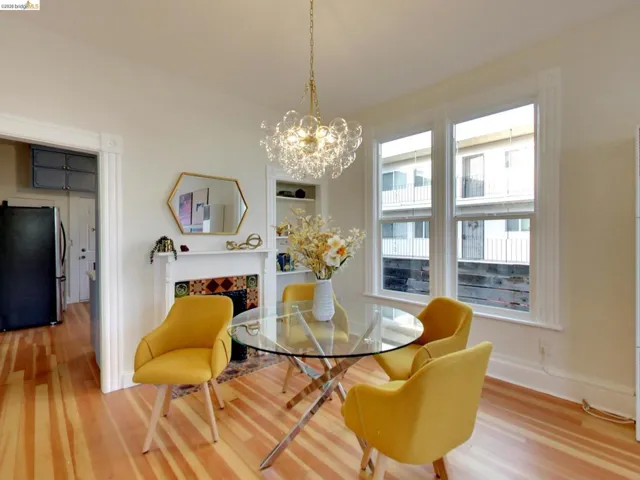 Fireplace with decorative tile surround and mantel, wood-finish flooring, glass globe chandelier, and built-in shelving