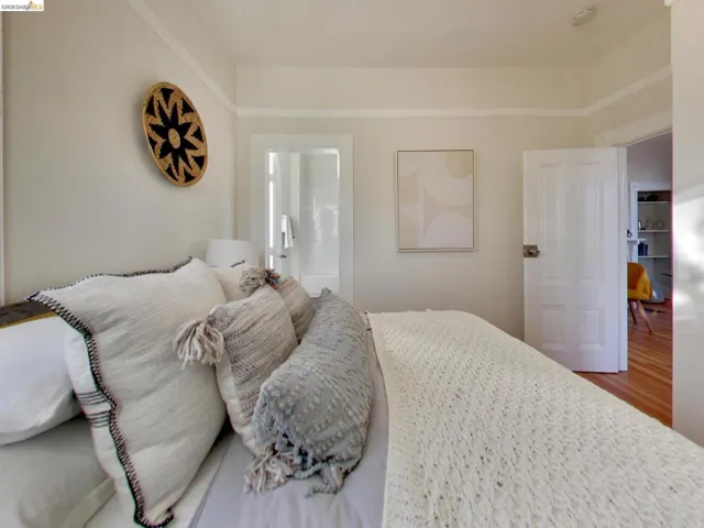Room featuring neutral wall paint, crown molding, a paneled door with metal hardware, and wood-finish flooring