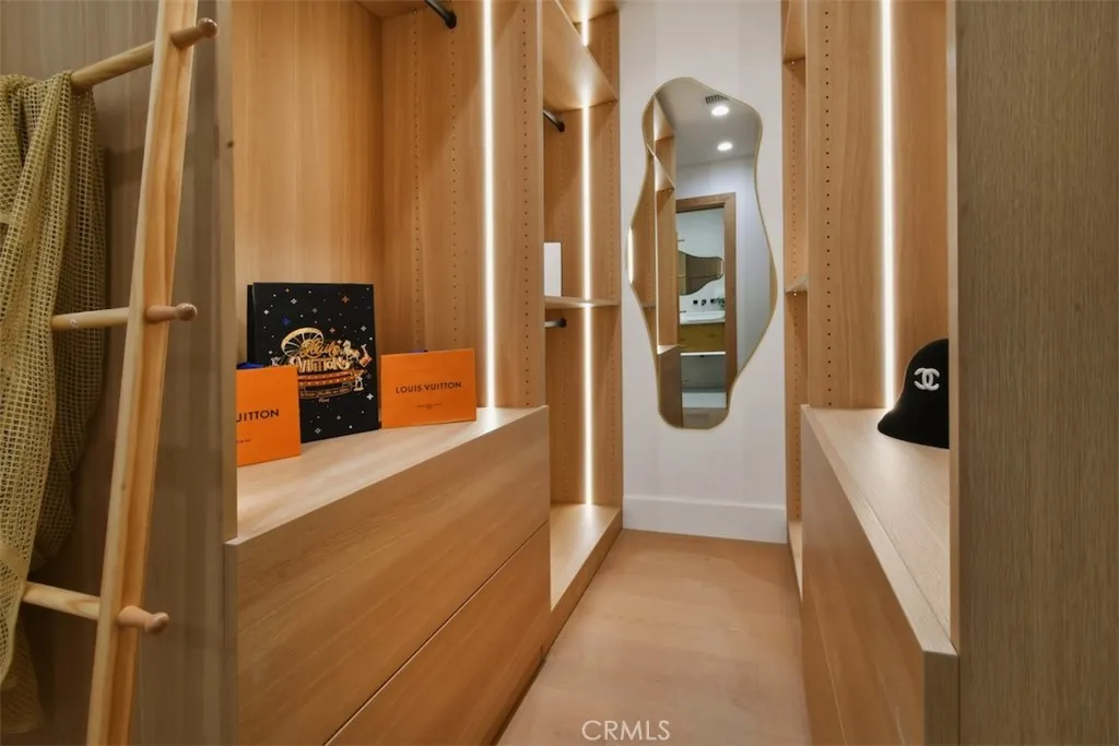 Detailed view of custom built-in primary closet organizer offering extensive storage and floating vanity space. Detailed view of custom built-in primary closet organizer offering extensive storage and floating vanity space.