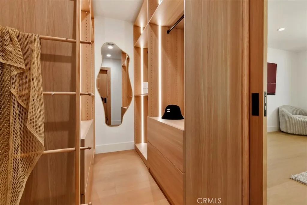 Expansive walk-in primary closet featuring custom built-in wood shelving, hanging racks, and drawers. Expansive walk-in primary closet featuring custom built-in wood shelving, hanging racks, and drawers.