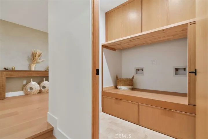 Laundry room - Custom built-in cabinetry and shelving nook with integrated accent lighting and wood paneling.