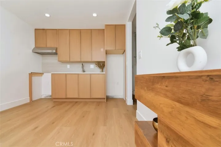 Bright and modern open-concept one bedroom ADU featuring a full kitchen with custom wood cabinetry, sleek flooring, and a spacious living area.