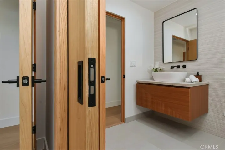 Updated bathroom showcasing a floating wood vanity, vessel sink, and modern matte black hardware.